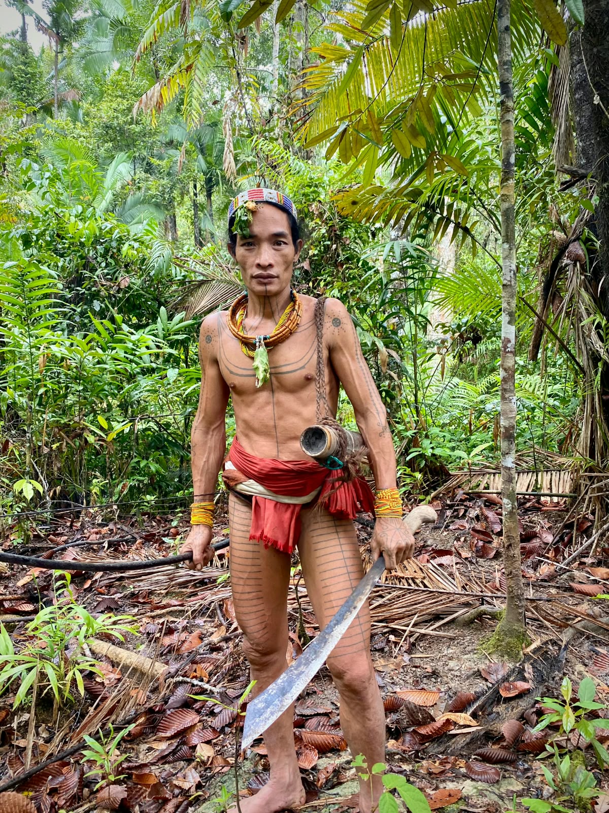 Mentawai men navigating river canoes through dense Sumatran rainforest